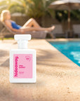 hideaway. Pink Sunset perfume 50ml bottle on a sunlit pool ledge on a summer afternoon