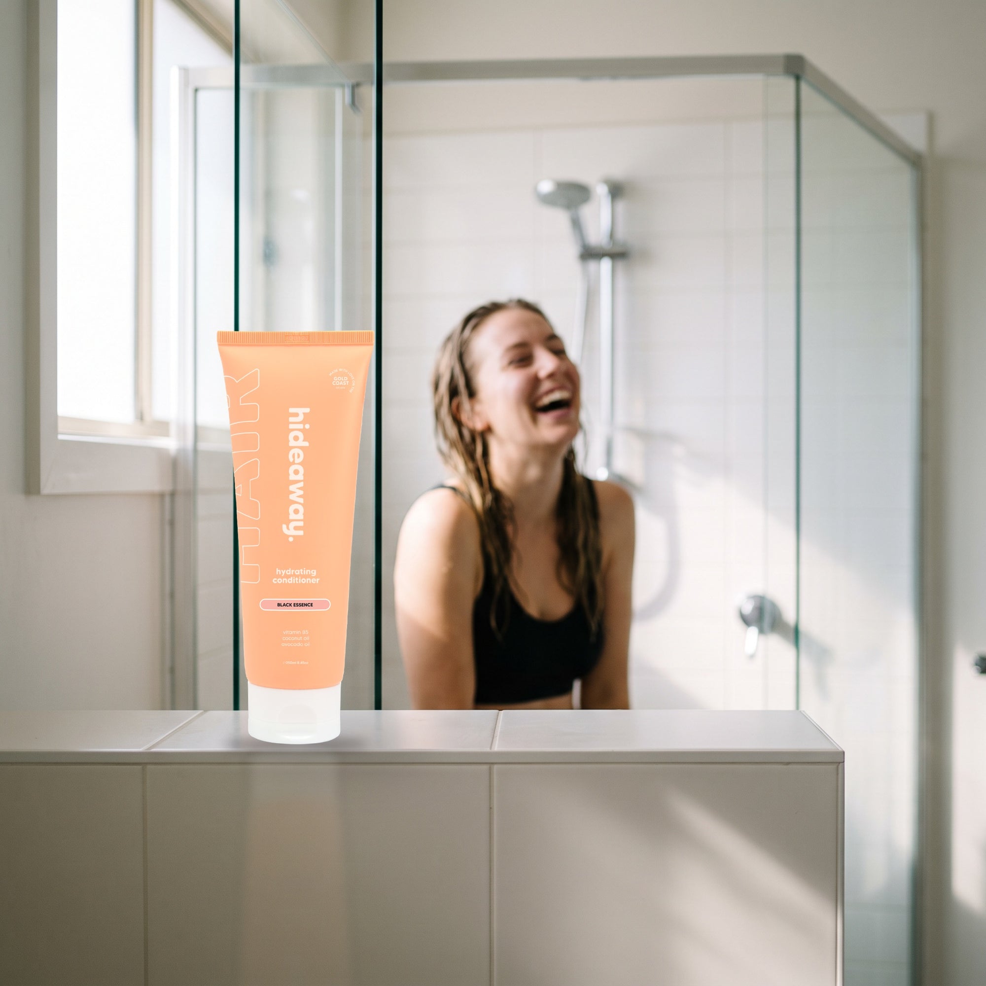 hideaway. Mini Black Essence Conditioner on a shower ledge in a bright bathroom