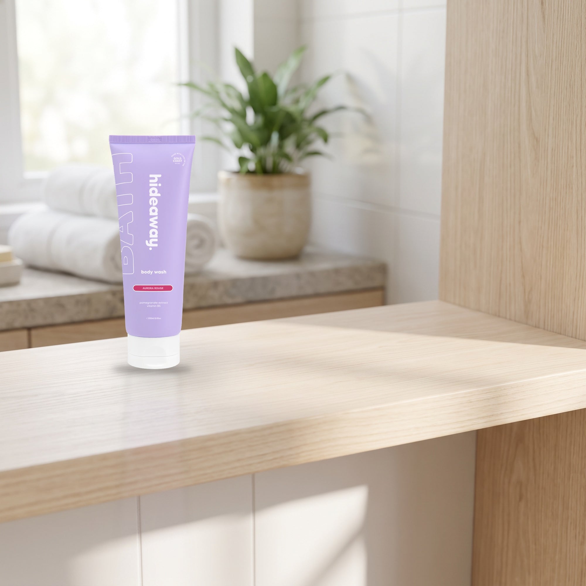 hideaway. Mini Aurora Rouge Body Wash on a timber bathroom shelf beside rolled towels