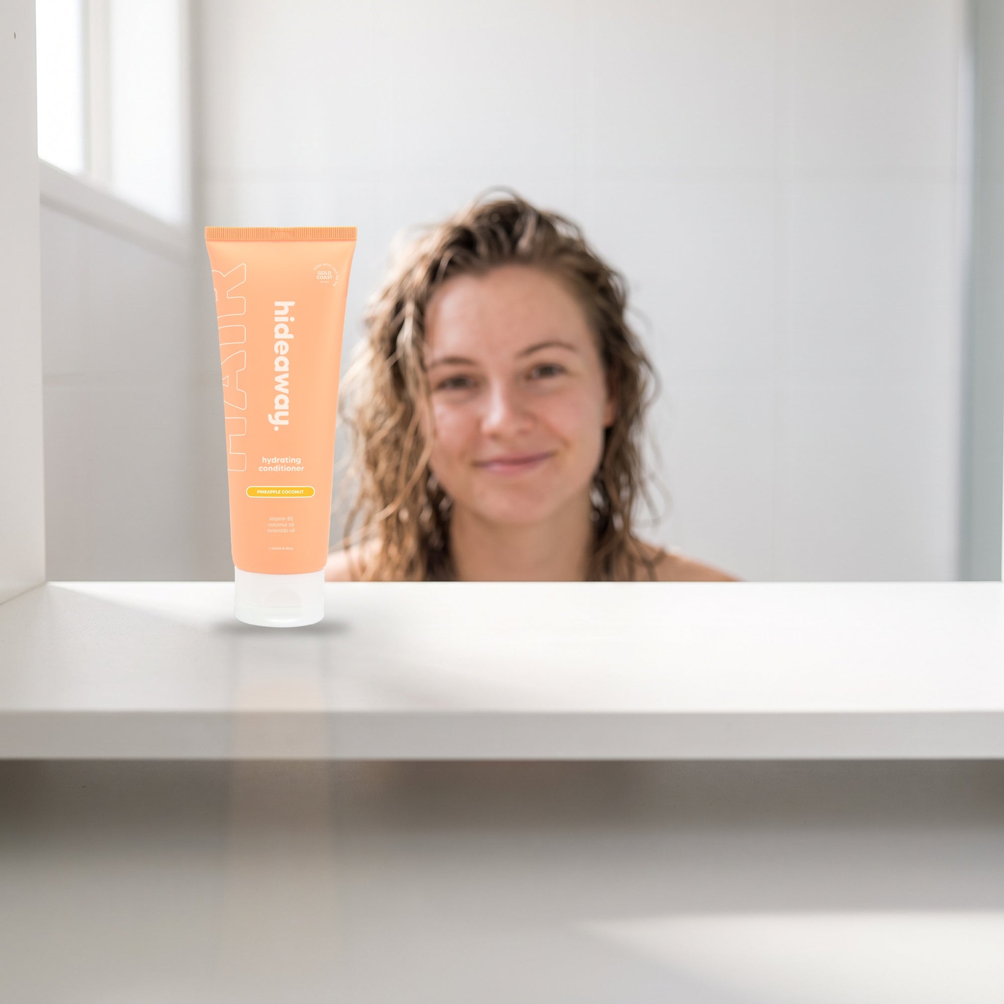 hideaway. Pineapple Coconut Conditioner on a white shelf in a bright tiled bathroom