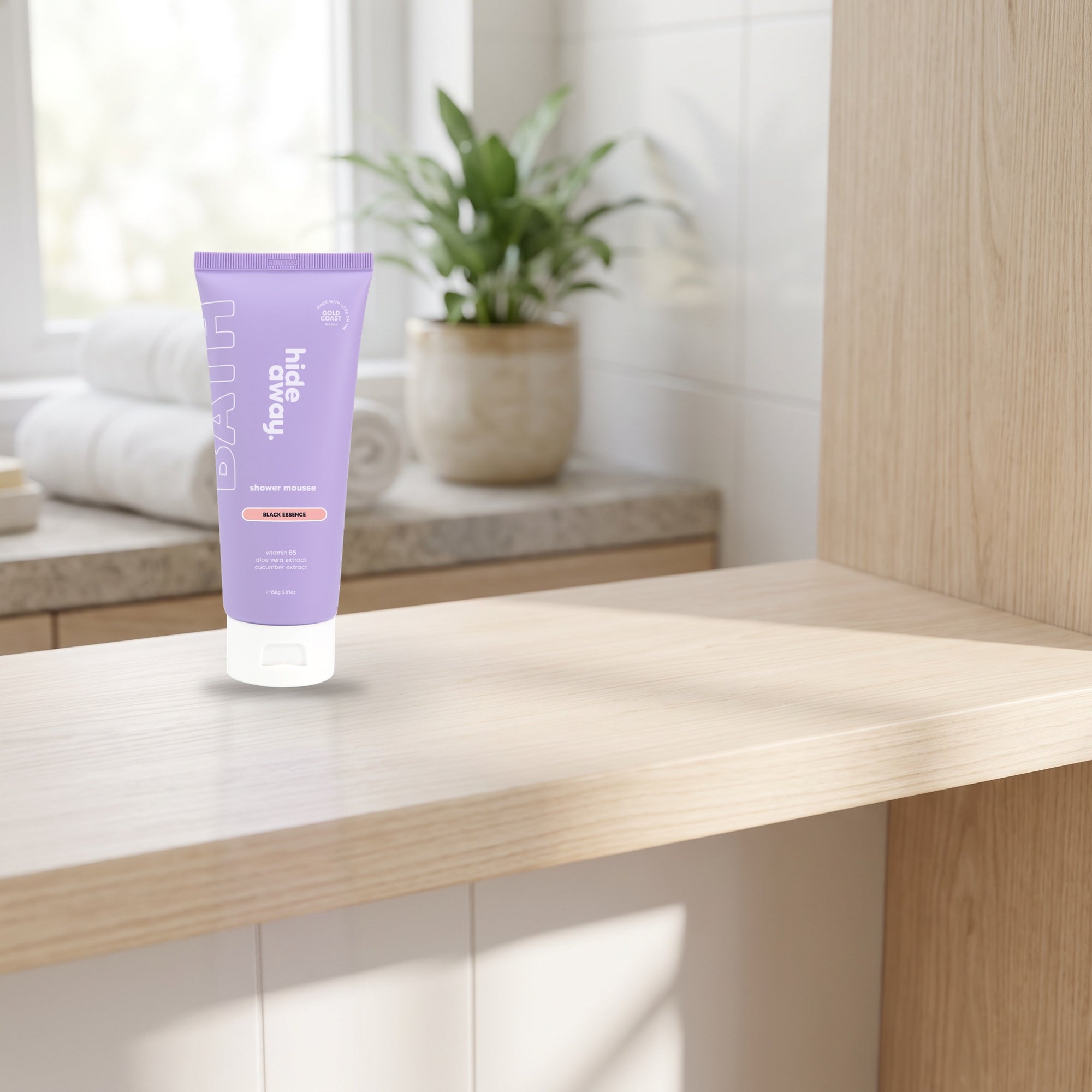 hideaway. Black Essence Shower Mousse on a timber bathroom shelf beside rolled towels