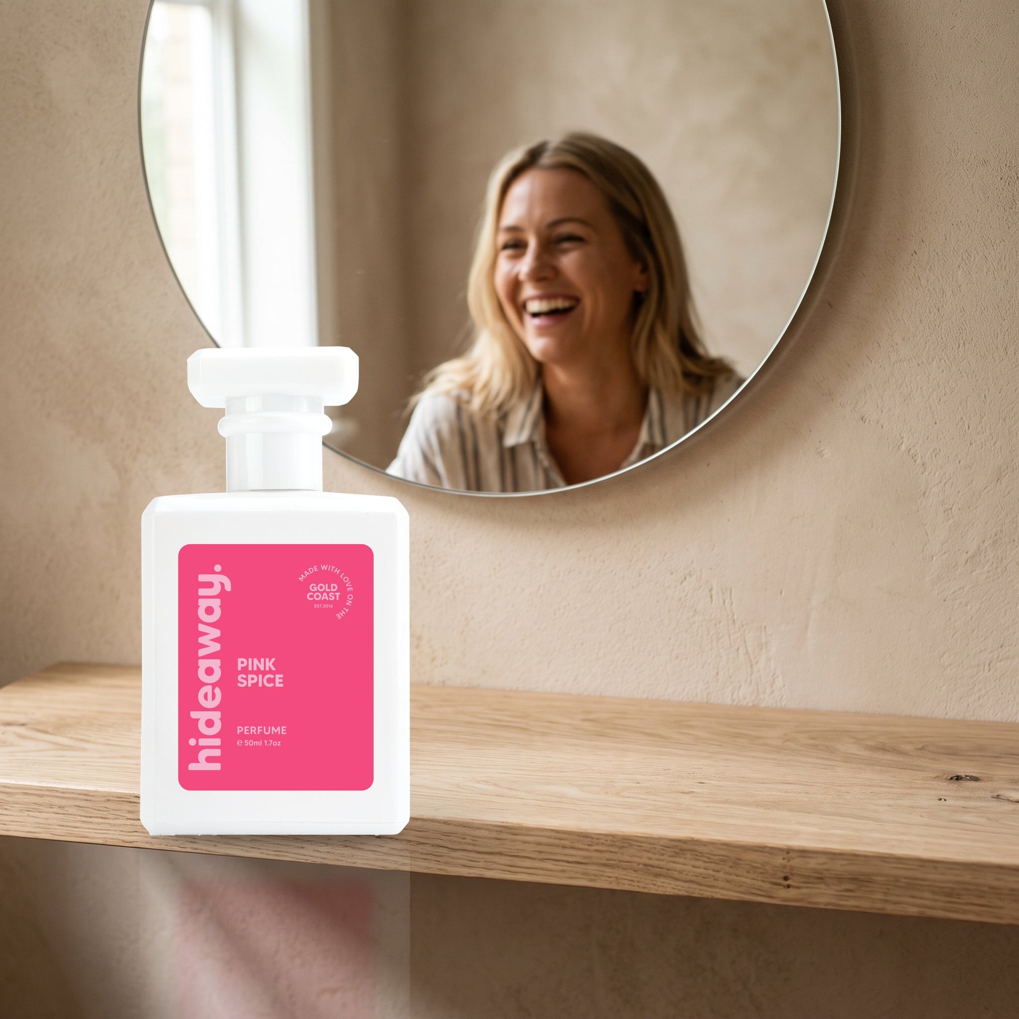 hideaway. Pink Spice perfume 50ml bottle on an oak shelf below a round mirror
