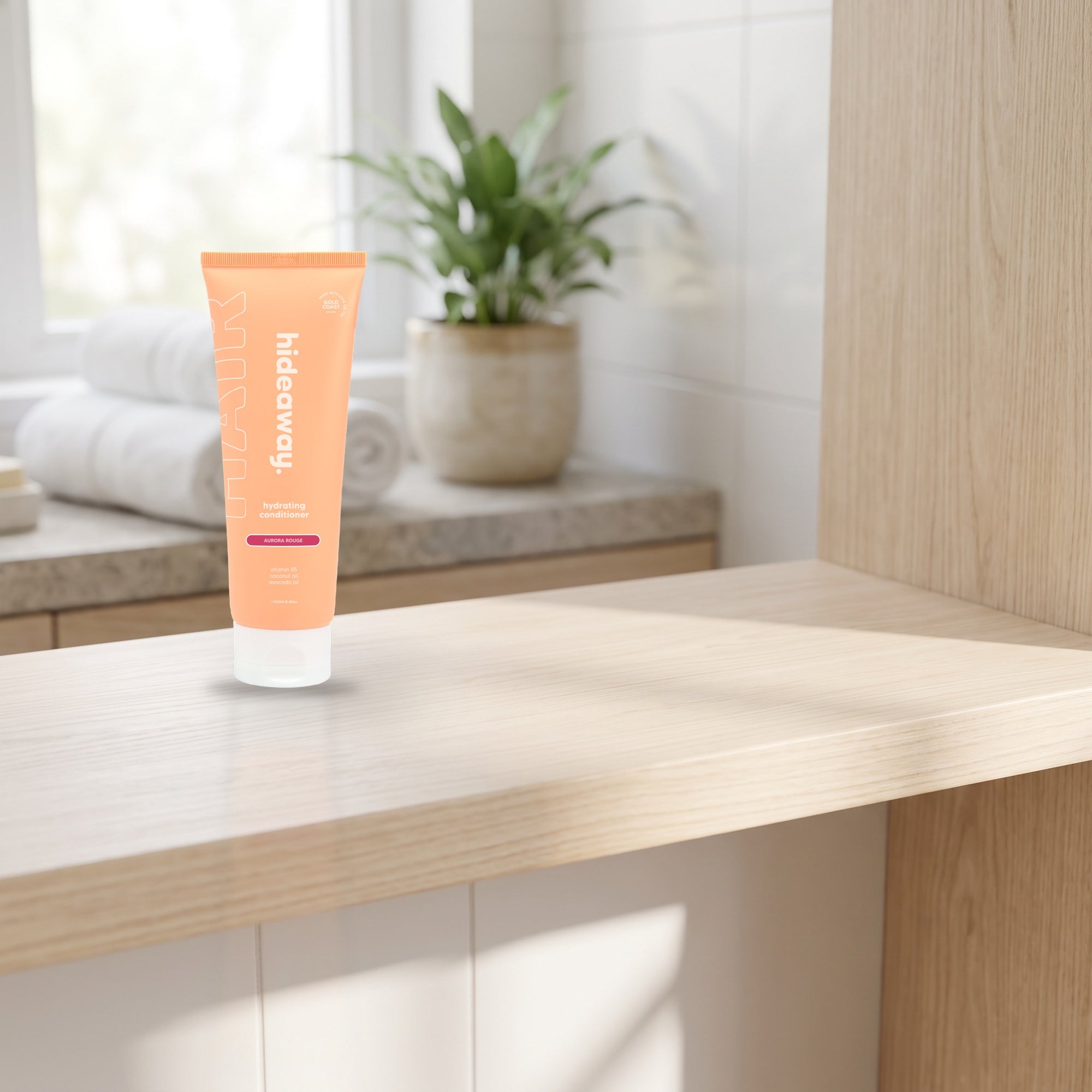 hideaway. Mini Aurora Rouge Conditioner on a timber bathroom shelf beside rolled towels