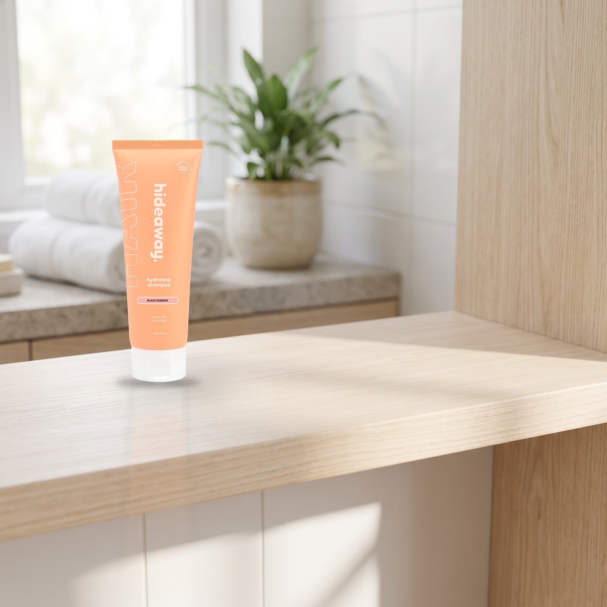 hideaway. Mini Black Essence Shampoo on a timber bathroom shelf beside rolled towels