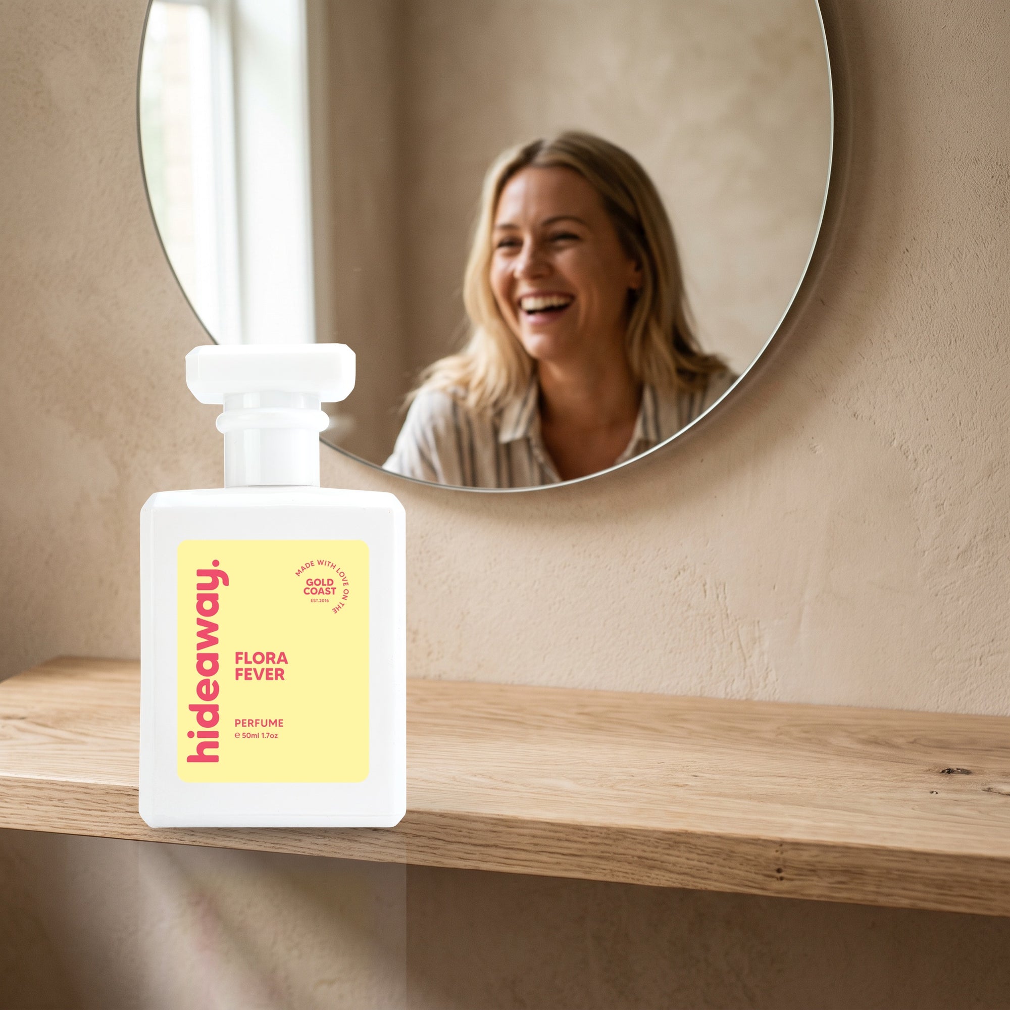 hideaway. Flora Fever perfume 50ml bottle on an oak shelf below a round mirror