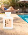hideaway. Slow Burn perfume 50ml bottle on a sunlit pool ledge on a summer afternoon