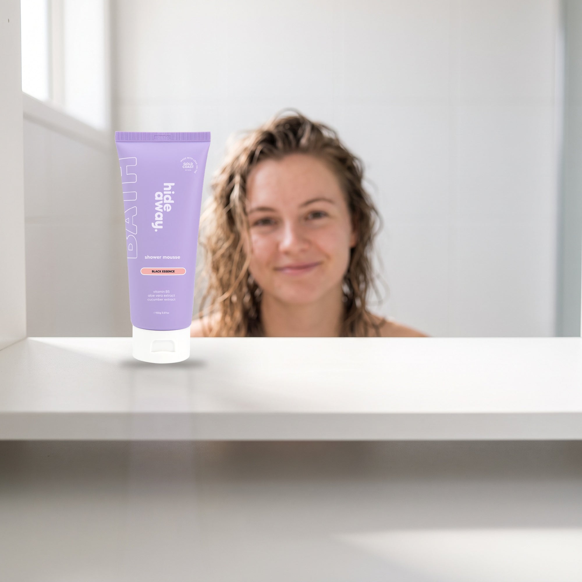 hideaway. Mini Black Essence Shower Mousse on a white shelf in a bright tiled bathroom